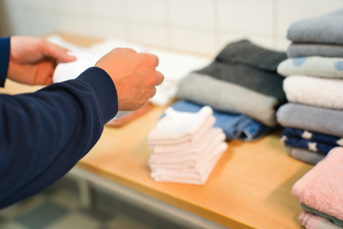 A man folds laundry in the laundry room